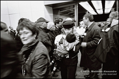 Dramatic picture of a French airline stewardess holding a child refugee in a busy airport. Picture is a link to www.FreePhotoCourse.com's Photographer Profiles series. Photo Credit: Matthieu Alexandre, (c) 2010, all rights reserved.